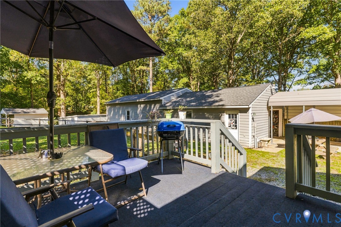 Elevated wooden deck featuring matching railings and stairs, exterior siding, and a metal-roofed carport