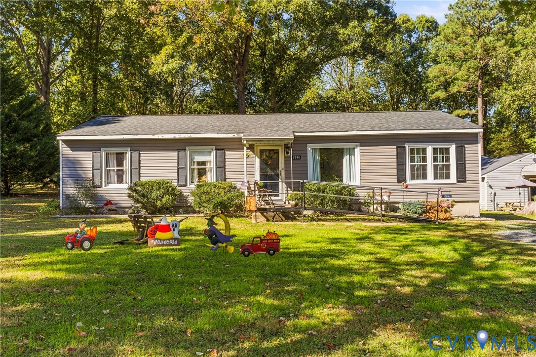 Ranch-style exterior with gray horizontal siding, dark decorative shutters, asphalt shingle roof, and a metal access ramp leading to the front entry Ranch-style exterior with gray horizontal siding, dark decorative shutters, asphalt shingle roof, and a metal access ramp leading to the front entry