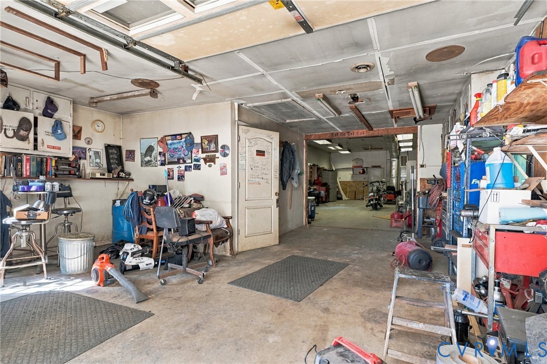 Expansive garage area featuring concrete flooring, integrated ceiling lighting, and a multi-section structural layout with a central pass-through door