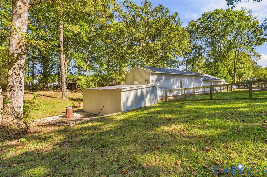 Expansive grounds featuring mature shade trees, a detached storage structure with metal siding, horizontal vinyl exterior siding, and perimeter post-and-rail fencing