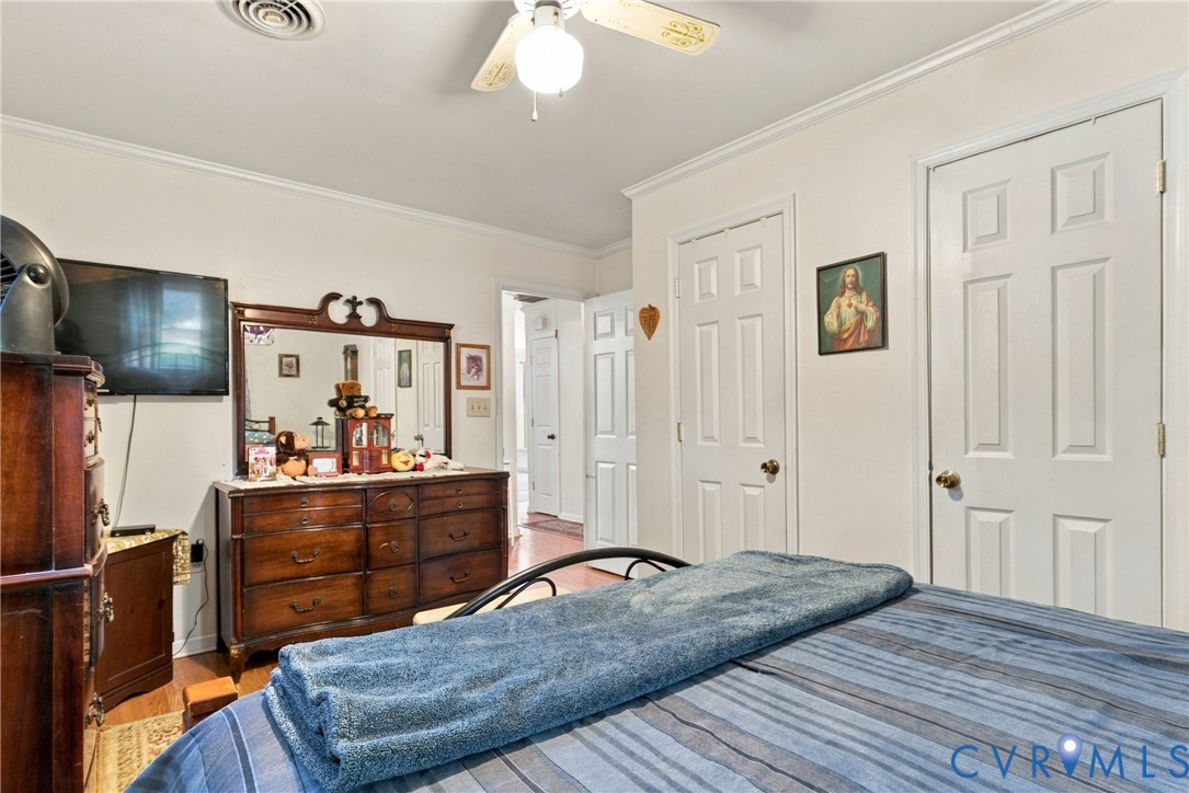Interior room featuring crown molding, neutral wall finishes, solid-core six-panel interior doors, and a ceiling-mounted light fixture with integrated fan