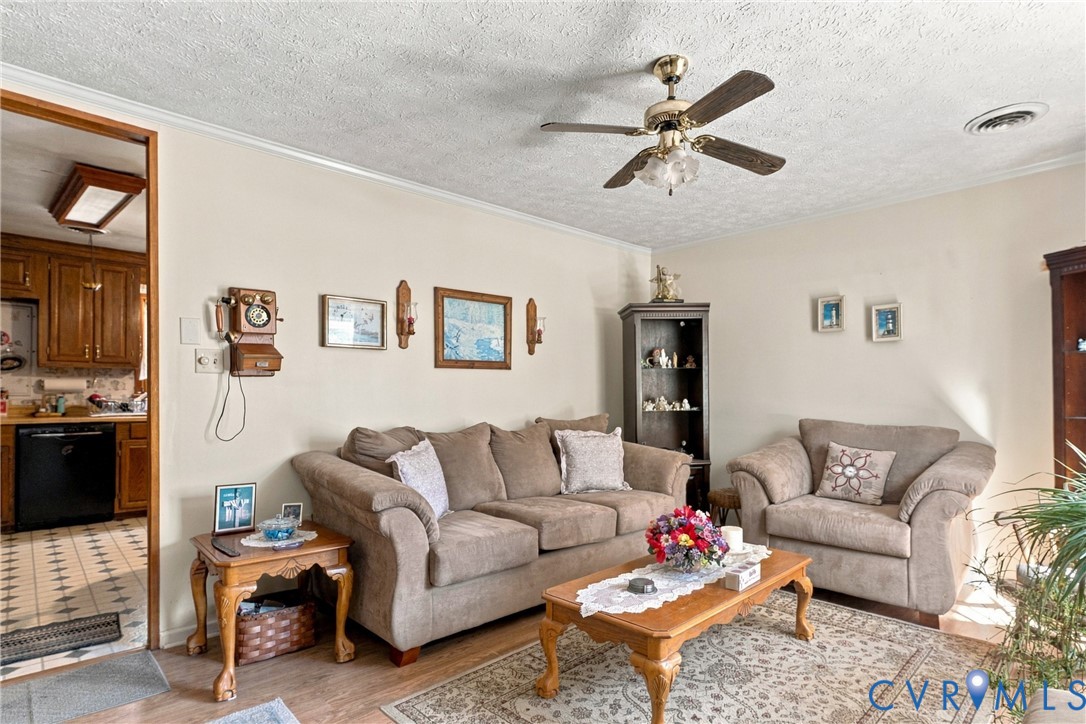 Living area featuring wood-finish flooring, a ceiling fan with integrated lighting, and a tall built-in corner cabinet