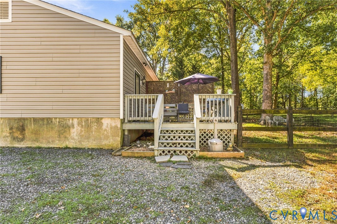 Raised wooden deck featuring lattice skirting, a privacy screen, and stairs with handrails