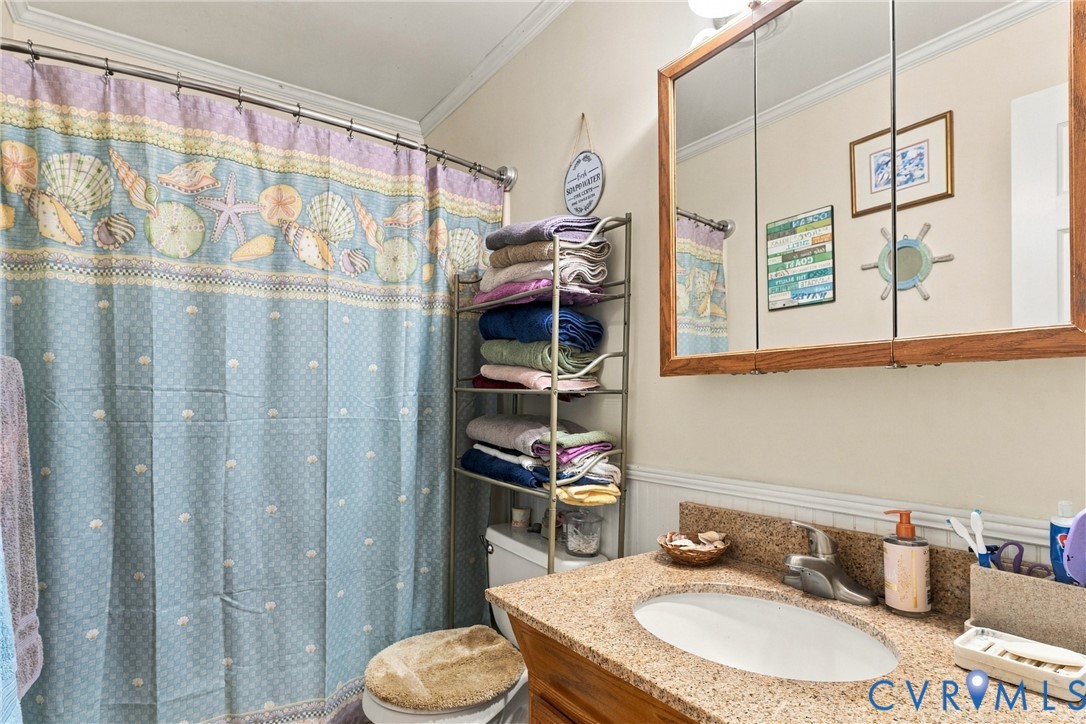 Bathroom featuring a vanity with a stone-finish countertop, undermount sink, and wood-framed medicine cabinet