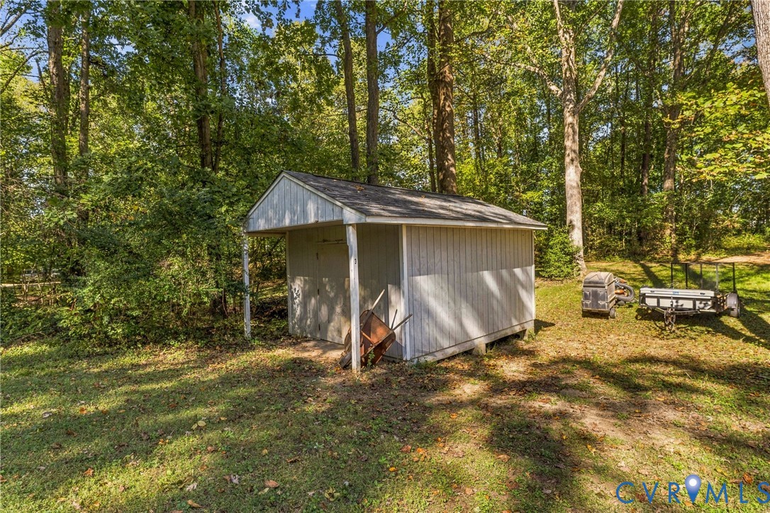 Storage shed with vertical wood siding, asphalt shingle gable roof, and open-front bay