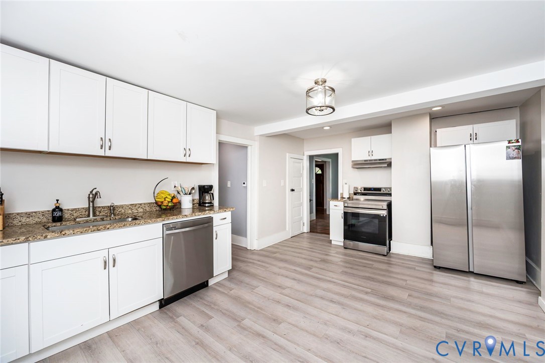 Kitchen featuring white cabinetry, stone-finish countertops, stainless steel appliances, and wood-finish flooring Kitchen featuring white cabinetry, stone-finish countertops, stainless steel appliances, and wood-finish flooring