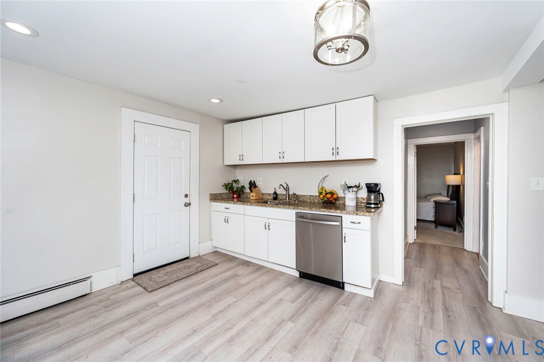 Kitchenette featuring white cabinetry, stone-finish countertops, stainless steel dishwasher, wood-finish flooring, and a glass-accented ceiling light fixture