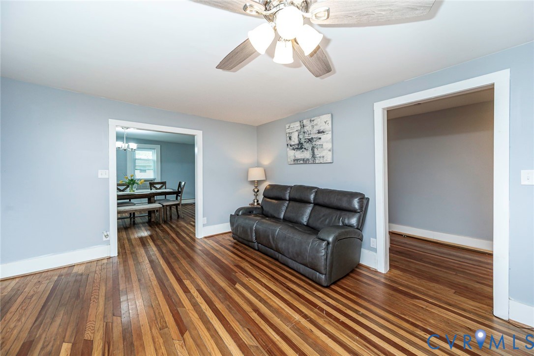 Wood-finish flooring, multi-tonal hardwood planks, ceiling fan with light fixture, and wide decorative door casing