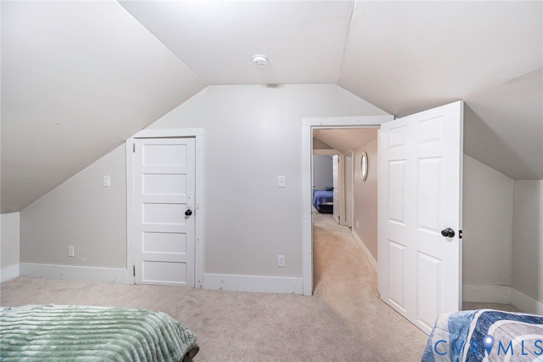 Sloped ceiling architecture featuring neutral-toned carpet, a five-panel interior door, and a double-panel door