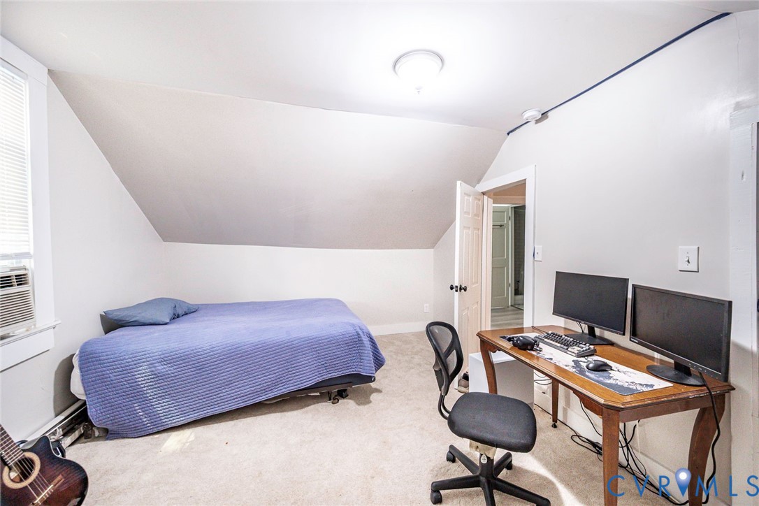 Sloped ceiling architecture with neutral wall tones, wall-to-wall carpeting, and a flush-mount ceiling light fixture