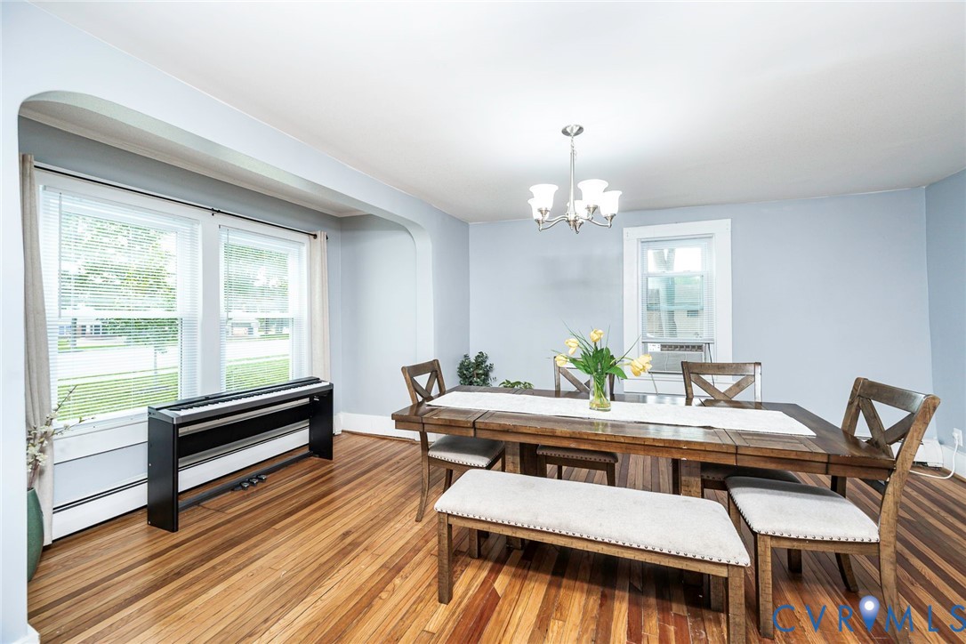Dining area featuring natural wood-finish flooring, an arched cased opening, and a multi-arm chandelier Dining area featuring natural wood-finish flooring, an arched cased opening, and a multi-arm chandelier