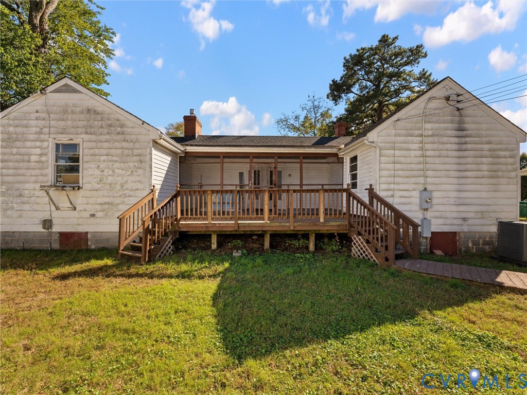 Exterior view featuring a rear screened-in porch with wood railings and dual access staircases, complemented by a roof with two chimneys and white siding