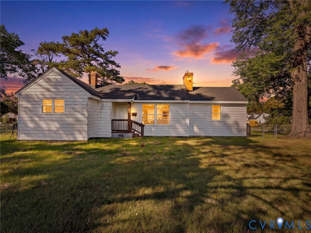 Single-story residence featuring horizontal siding, a gabled roofline, dual masonry chimneys, and a covered front entry Single-story residence featuring horizontal siding, a gabled roofline, dual masonry chimneys, and a covered front entry
