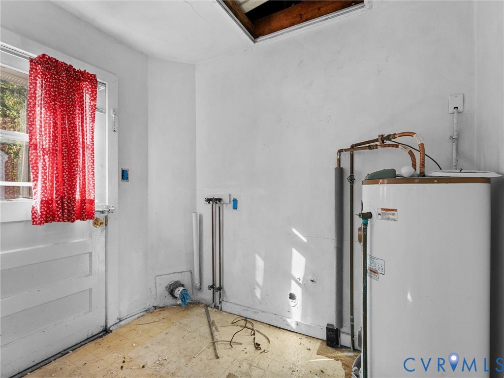 Utility area featuring an exterior access door, a standard electric water heater, and exposed plumbing connections