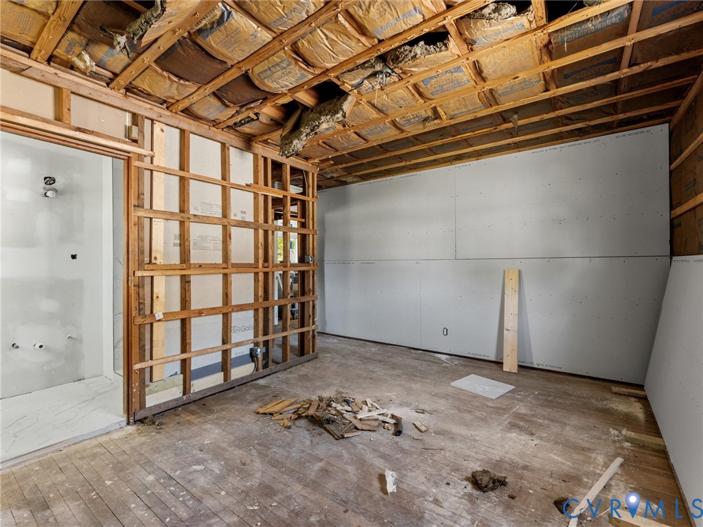Interior space featuring exposed wood framing, installed drywall panels, and open-joist ceiling with insulation