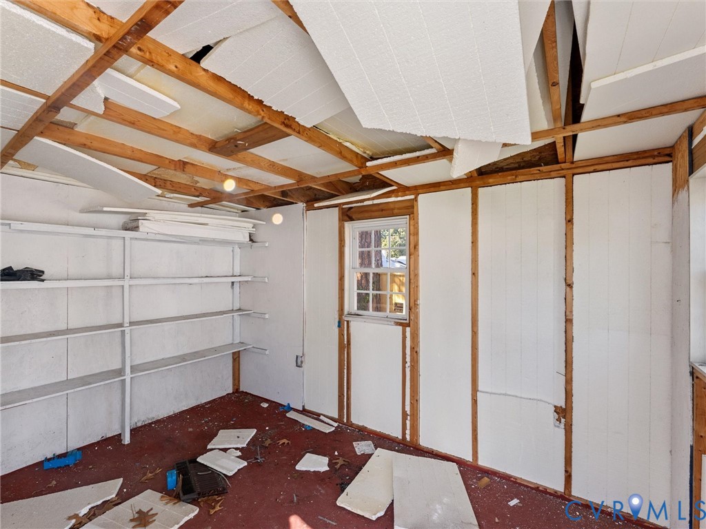 Interior space featuring exposed wood framing, built-in wooden shelving, and a single-hung window