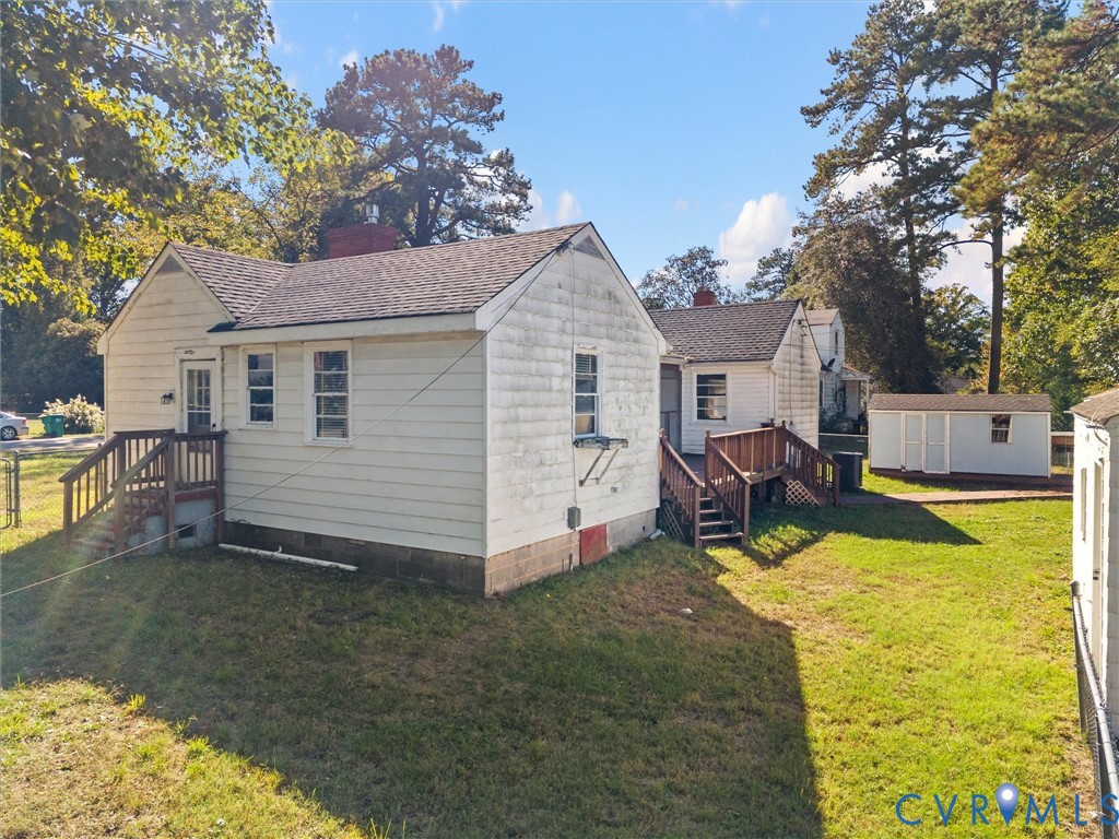 Exterior featuring horizontal siding, asphalt shingle roofing, two elevated wood decks, and a detached storage structure set on a grass-covered lot