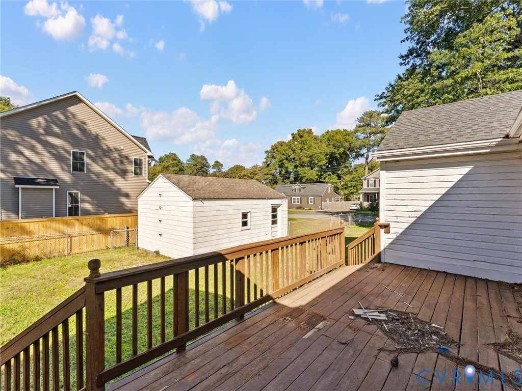 Elevated wooden deck with balustrades, detached storage building, and fenced backyard area