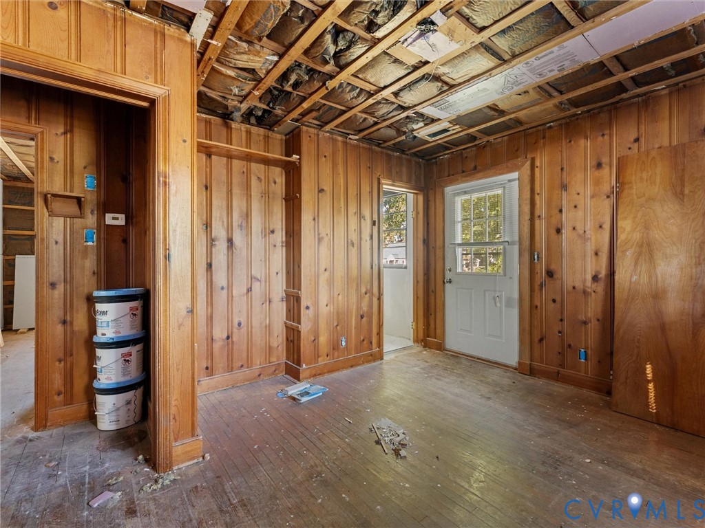 Interior space featuring natural wood paneling, exposed ceiling joists, hardwood flooring, and a glass-paneled exterior door