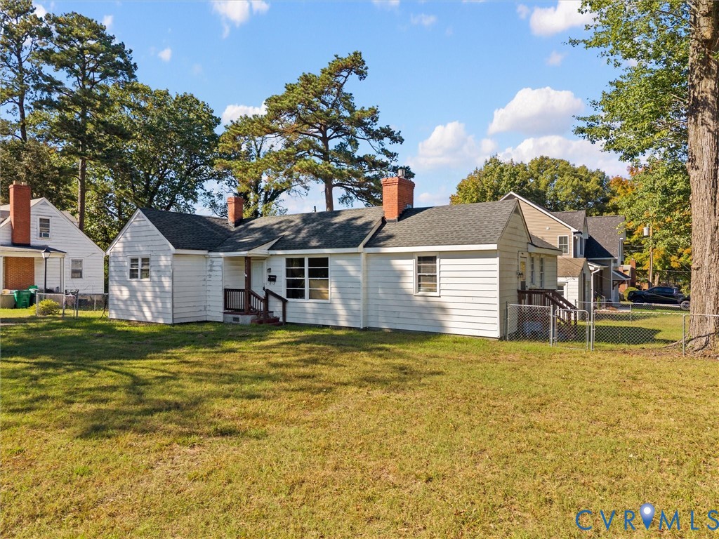 Single-story residence featuring a white lap siding exterior, asphalt shingle roof, two brick chimneys, and an expansive lawn