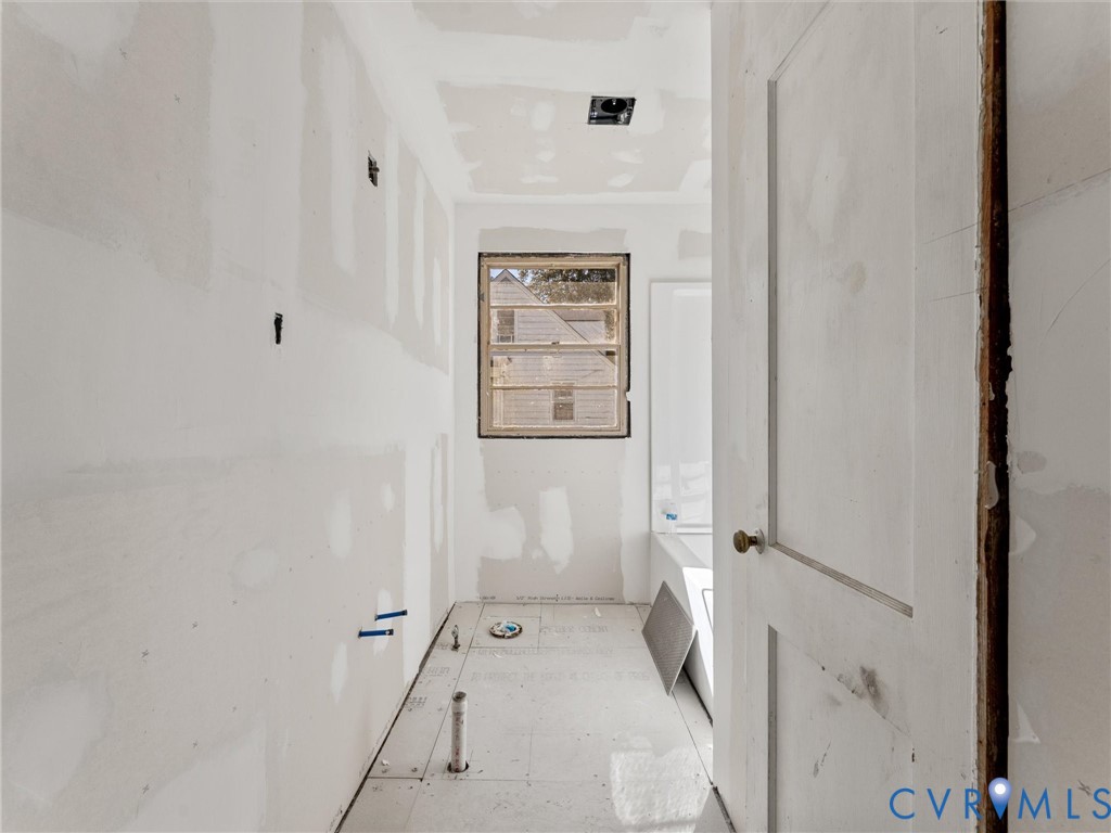 Interior space featuring unfinished drywall, subflooring, a single-hung window, and a recessed ceiling light fixture