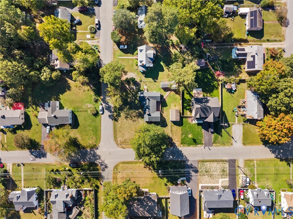 Aerial perspective featuring suburban neighborhood lots with mature trees and paved street infrastructure