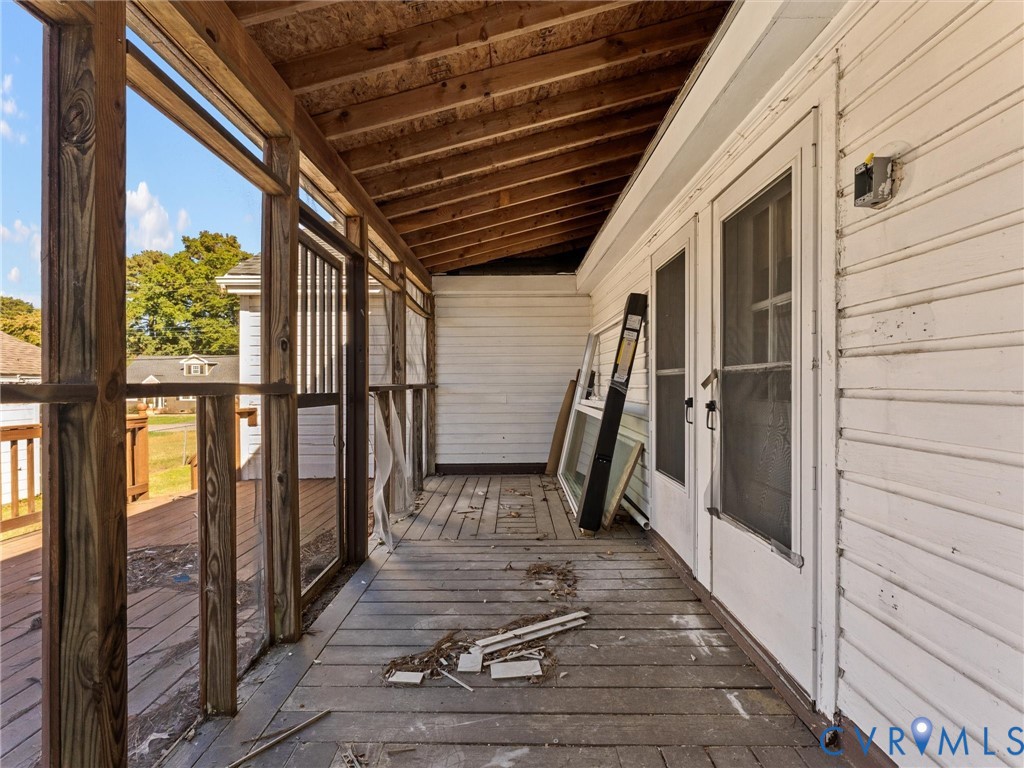 Screened-in porch featuring wood decking, exposed rafter ceiling, and dual screen entry doors