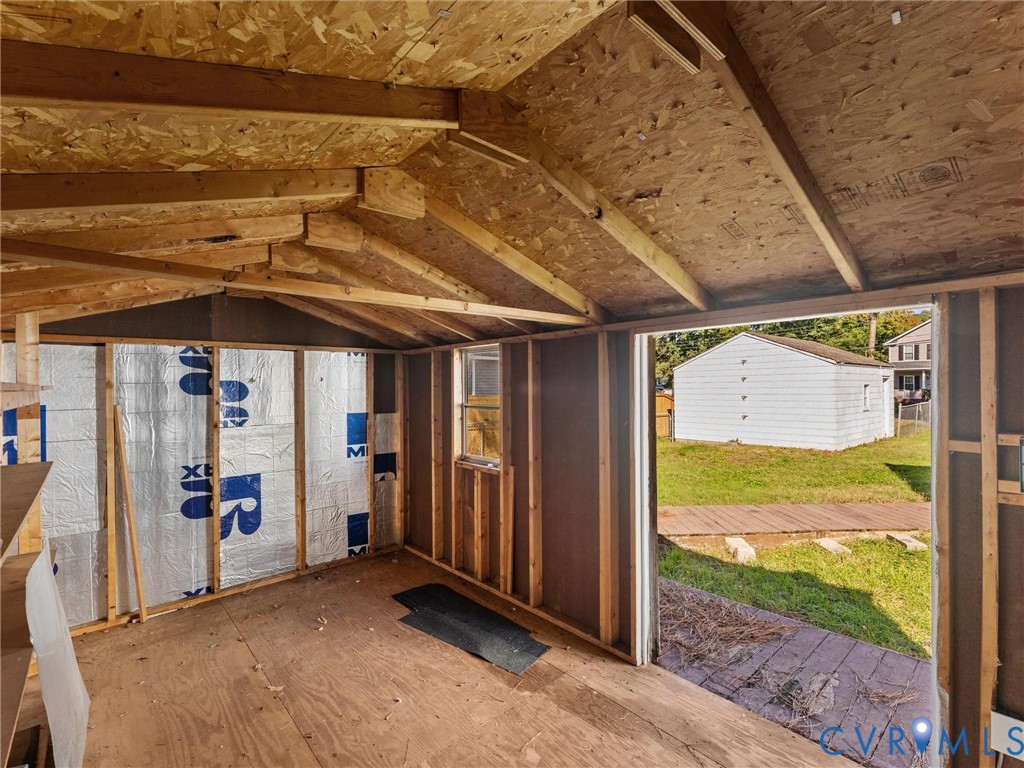 Outbuilding with exposed wood framing, metallic insulation panels, single-pane window, and exterior wood deck