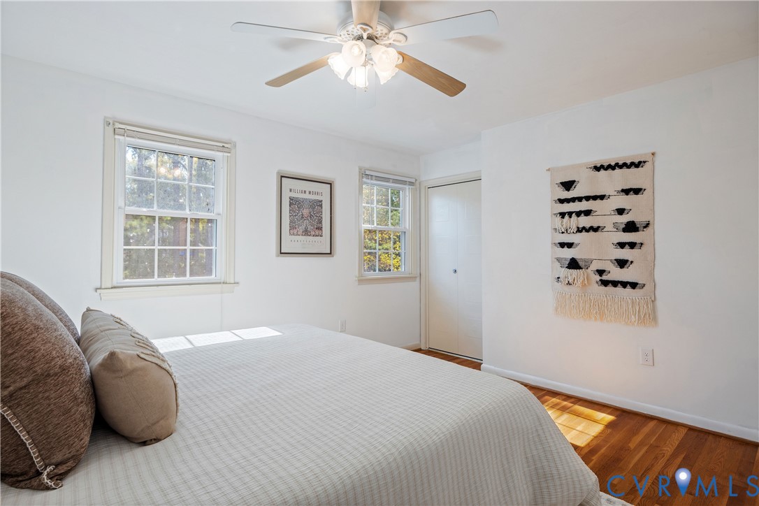 Neutral interior featuring wood-finish flooring, double-hung windows, and a ceiling fan with integrated light fixture