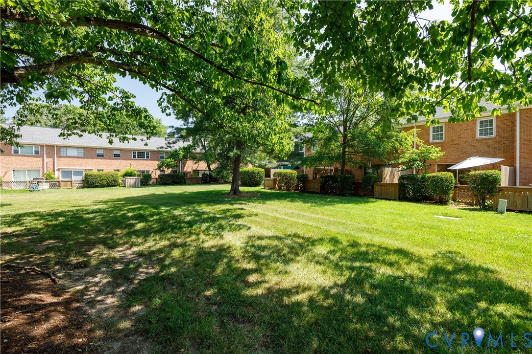 Expansive shared green space featuring mature shade trees, brick exterior facades, and wood privacy fencing