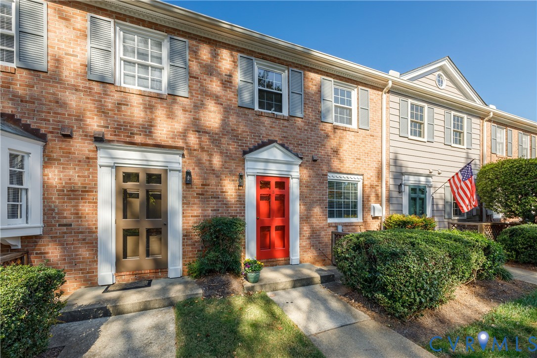 Classic brick townhouse exterior featuring multi-pane windows, louvered shutters, decorative door surrounds, and dual-entry design Classic brick townhouse exterior featuring multi-pane windows, louvered shutters, decorative door surrounds, and dual-entry design
