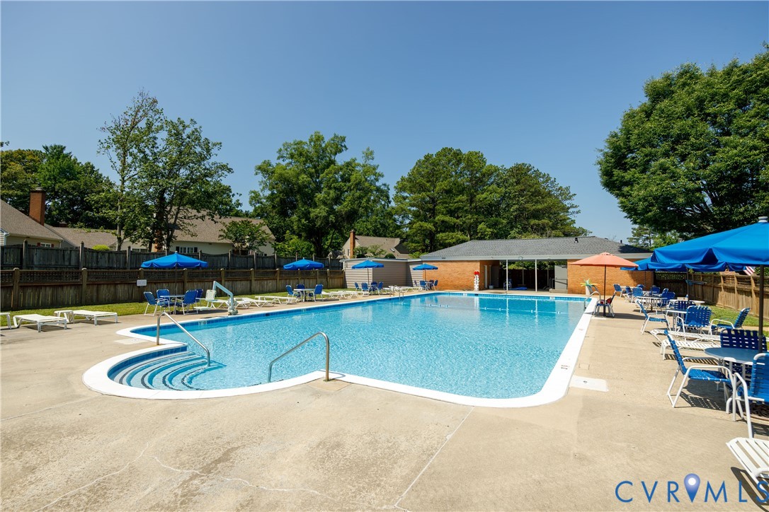 Rectangular outdoor swimming pool featuring concrete decking, stepped entry, stainless steel handrails, and a brick-constructed pavilion