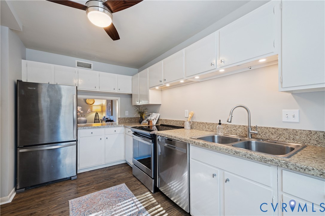 Kitchen featuring white cabinetry, stone-finish countertops, stainless steel appliances, double-basin sink with pull-down faucet, and wood-finish flooring