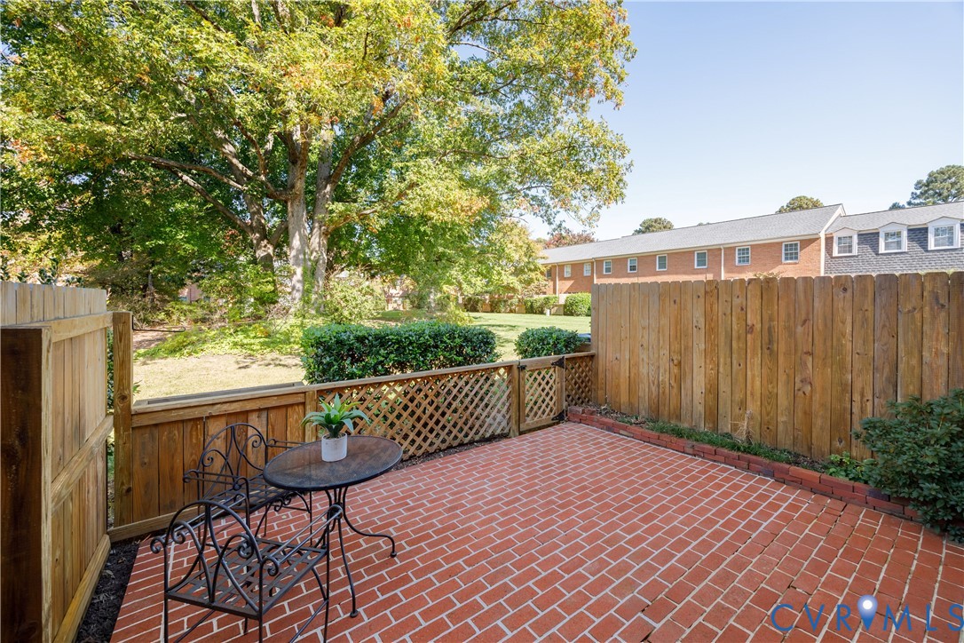 Private brick patio enclosed by a wood-slat fence with integrated lattice detailing and mature surrounding trees