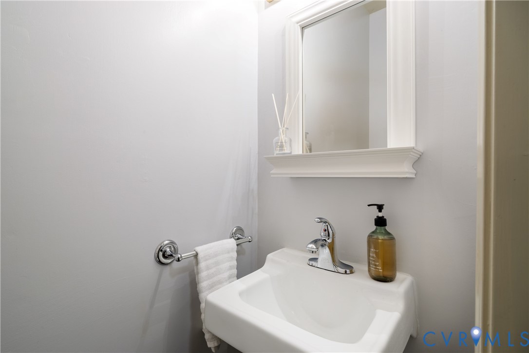 Wall-mounted white basin sink featuring a chrome faucet, complemented by a framed mirror with an integrated shelf and a chrome towel bar