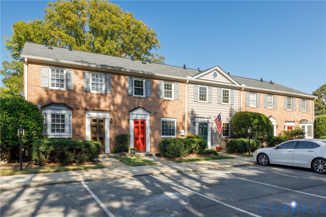 Multi-unit residential exterior featuring a classic brick and horizontal siding faade, multi-pane windows with decorative shutters, pedimented entryways, and asphalt shingle roofing Multi-unit residential exterior featuring a classic brick and horizontal siding faade, multi-pane windows with decorative shutters, pedimented entryways, and asphalt shingle roofing