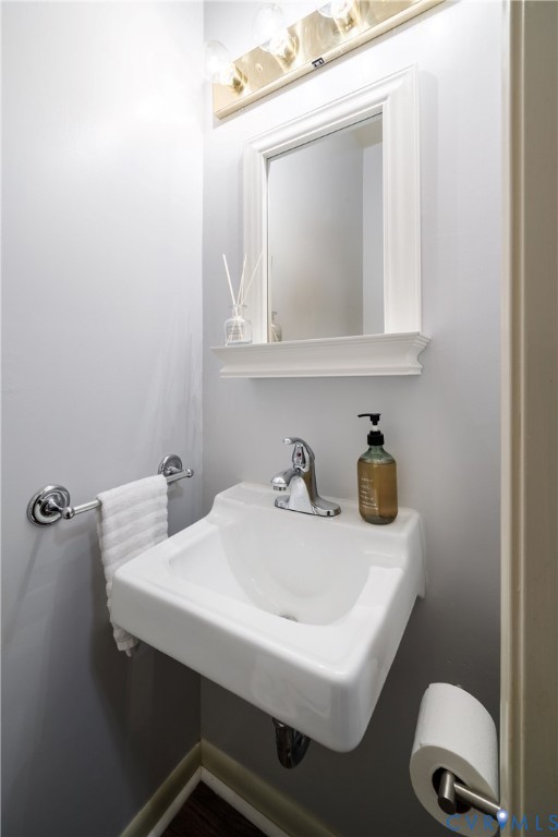 Wall-mounted porcelain sink with polished chrome faucet, framed mirror with integrated ledge, and polished chrome hardware