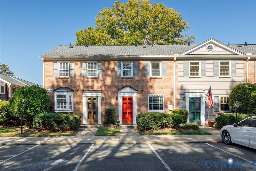 Brick and horizontal siding exterior featuring a gabled roofline, multi-pane windows, and individual entry doors with colonial-style trim Brick and horizontal siding exterior featuring a gabled roofline, multi-pane windows, and individual entry doors with colonial-style trim