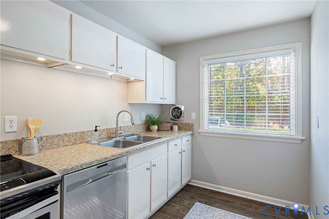 Kitchen featuring white cabinetry, stone-finish countertops, stainless steel dual-basin sink with arched faucet, and wood-finish flooring