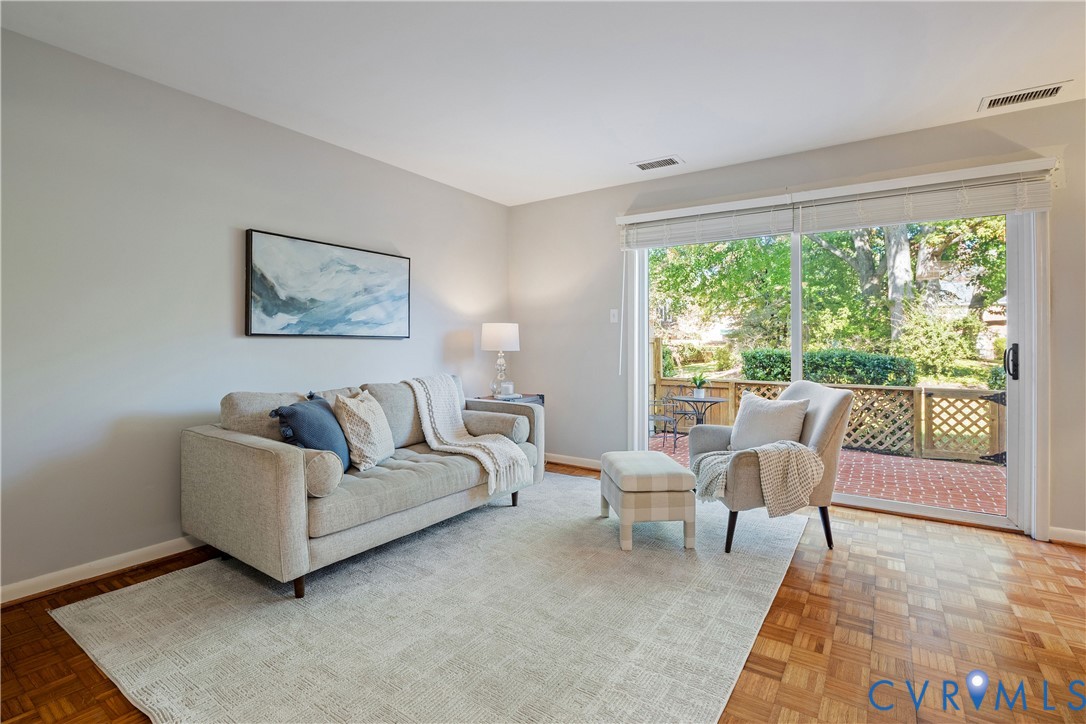 Parquet wood-finish flooring, neutral wall tones, and floor-to-ceiling sliding glass doors opening to a brick-paved patio