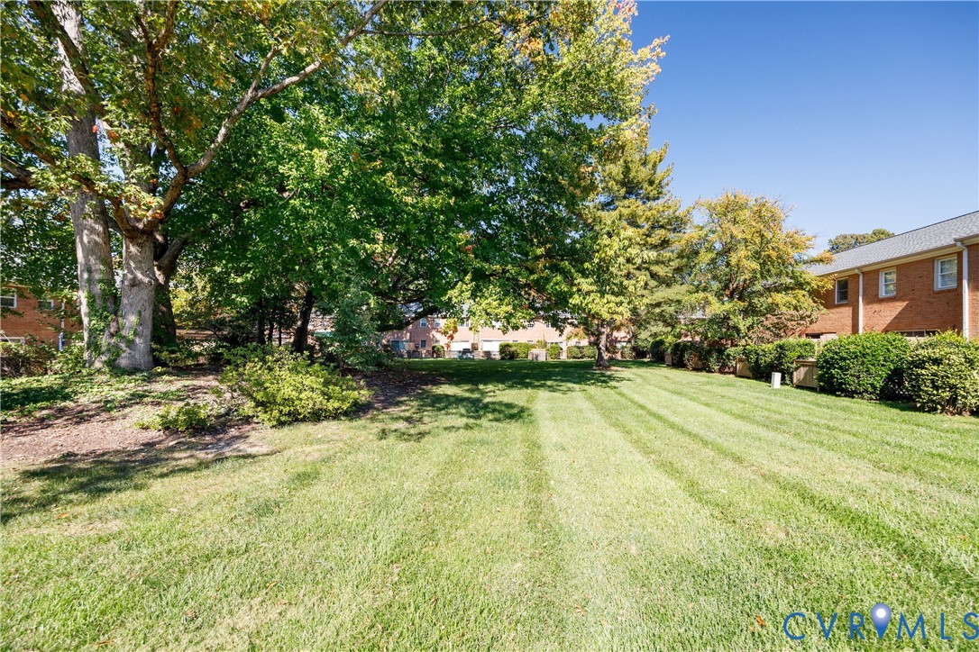 Expansive lawn area featuring mature trees, manicured shrubs, and brick exterior structures