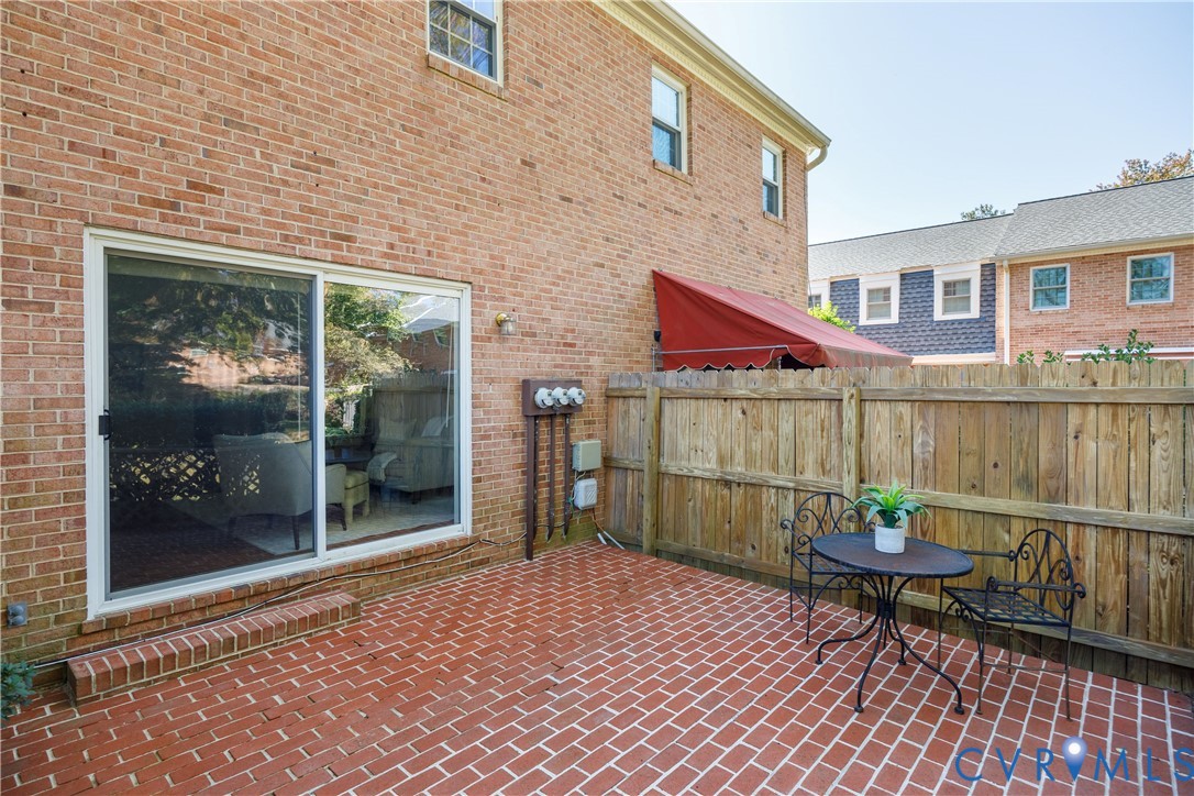 Brick patio with a sliding glass door and a wood privacy fence