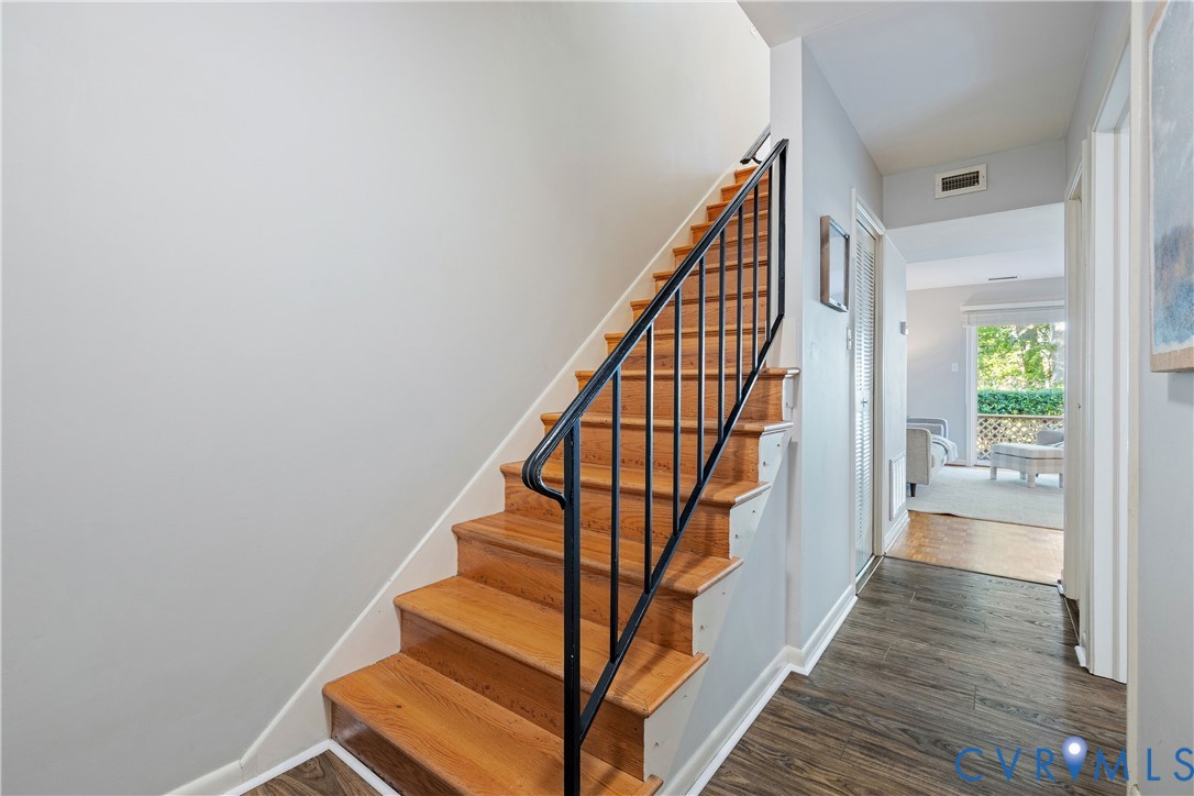 Staircase featuring wood treads and a black metal railing, complemented by wood-finish flooring Staircase featuring wood treads and a black metal railing, complemented by wood-finish flooring
