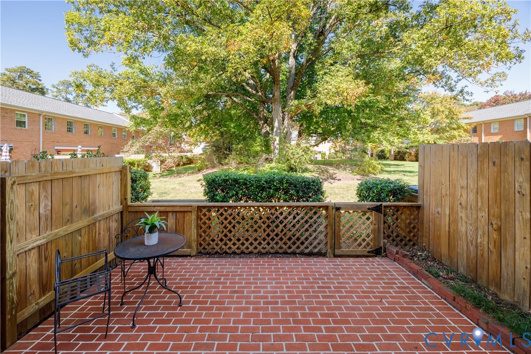 Private patio featuring brick pavers, a wood privacy fence, and a decorative lattice gate