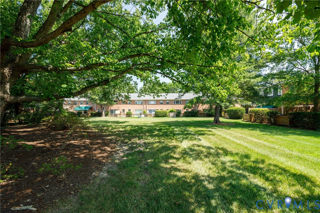 Expansive lawn area featuring mature trees, landscaped shrubbery, and brick building exteriors