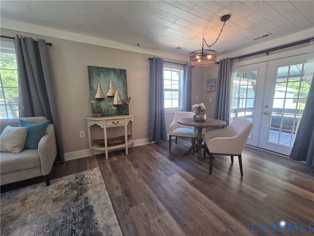 Wood-finish flooring, plank-style ceiling, multi-light industrial pendant fixture, and double French doors with grid glass panels