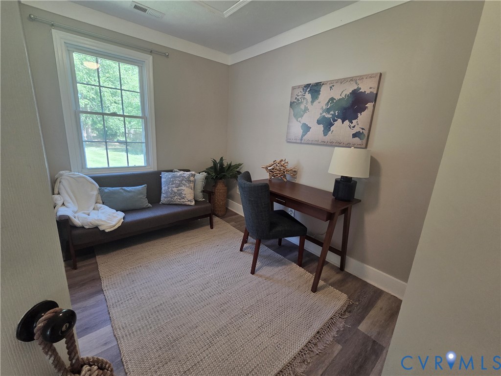 Neutral interior featuring wood-finish flooring, crown molding, and a multi-pane window with white casing