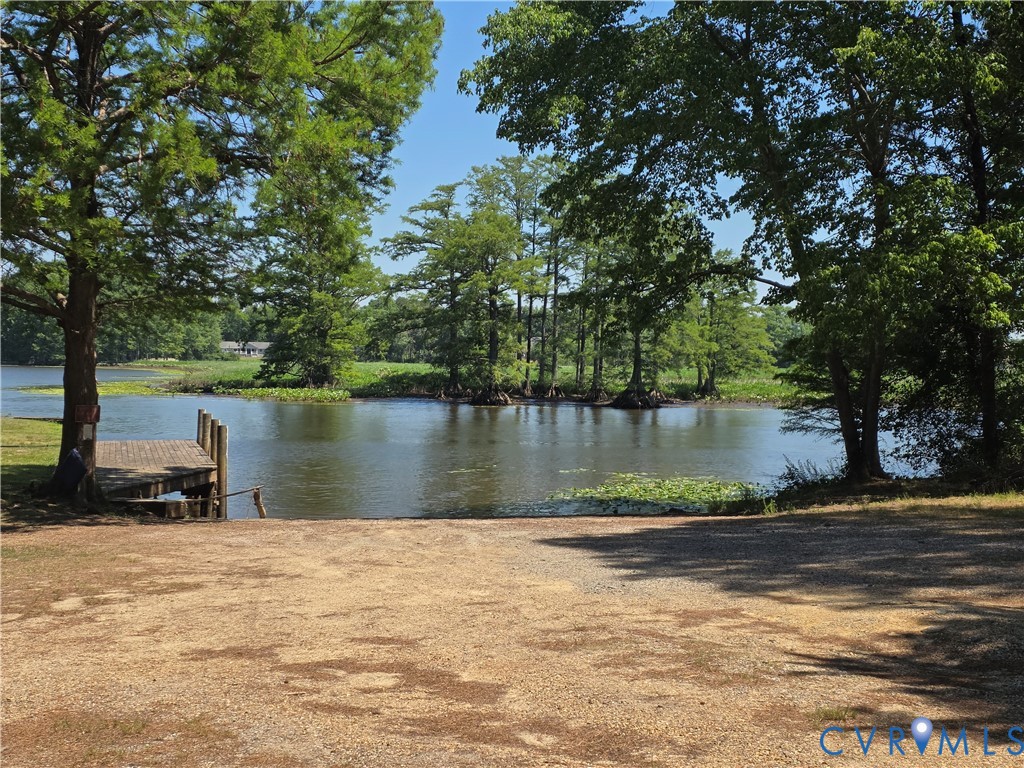 Waterfront property featuring a private wooden dock, a boat launch, and mature native trees