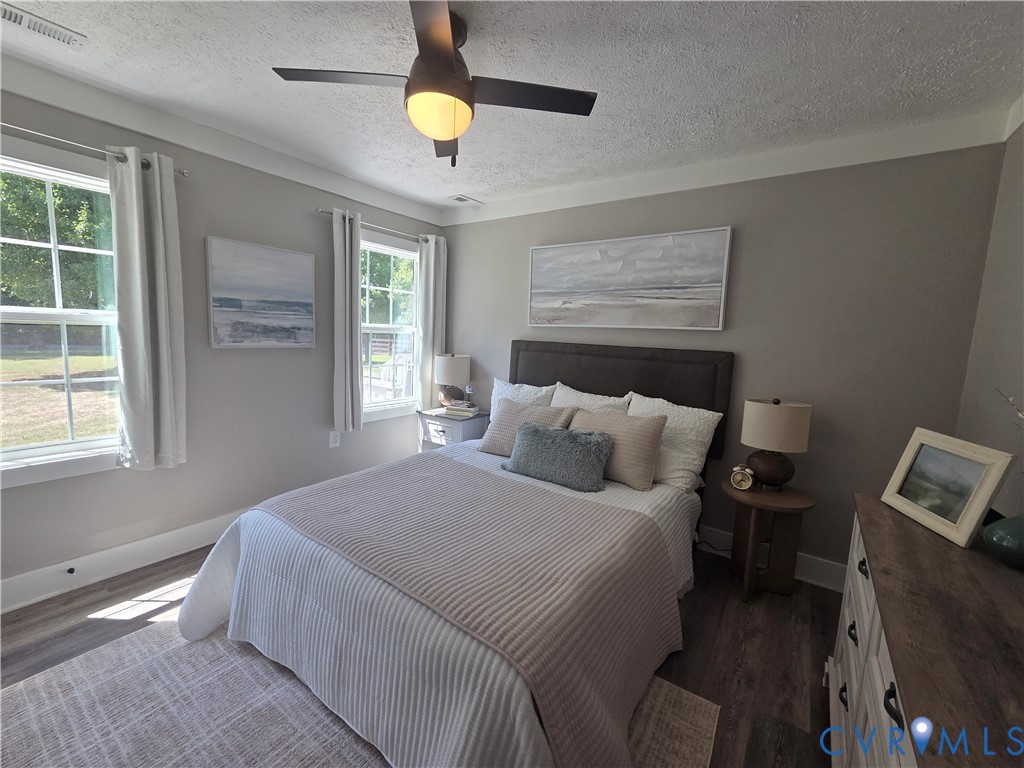 Neutral-toned interior featuring wood-finish flooring, multi-pane windows, and a ceiling fan with integrated lighting