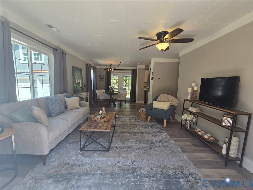 Living area featuring wood-finish flooring, a ceiling fan with integrated lighting, and glass-paneled double doors